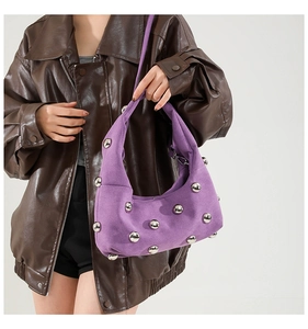 Detail of purple hobo bag with silver metal studs worn over a brown leather jacket