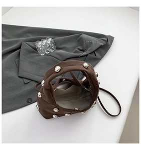 Detailed interior of dark brown suede bag with silver studs and inner pocket
