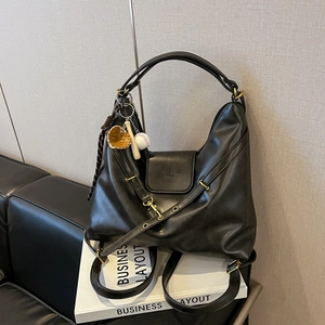 Retro black leather tote bag with gold hardware and baseball charm on display