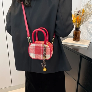 Red plaid wool tote bag with golden bell charm shown in a stylish lifestyle setting