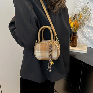 Plaid wool mini bowling bag with brown leather handles worn by a model in casual style
