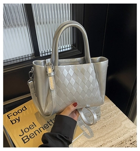 Detail of silver tote bag featuring quilted lattice pattern and dual top handles