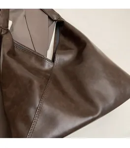 Close-up of vintage dark brown faux leather tote with detailed stitching and soft texture