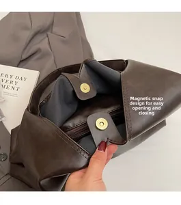 Detail of magnetic snap closure and internal zipper pocket on a brown tote bag