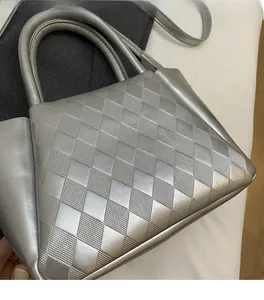 Close-up of silver quilted bucket bag showing 3D rhombus texture and smooth top handle