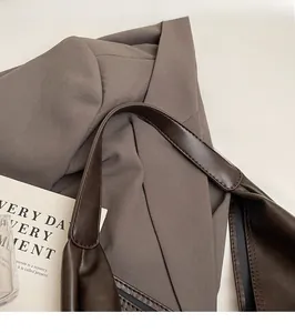 Detail of the dark brown leather shoulder strap with reinforced stitching on a tote bag