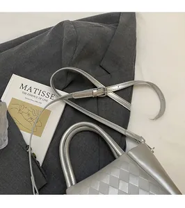 Detail of silver quilted crossbody bag with adjustable strap on a grey blazer suit