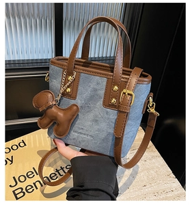 Detail of blue denim bucket bag with brown leather trim and golden metal hardware