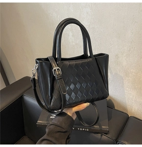 Detail of black quilted texture on leather handbag with silver hardware and handles