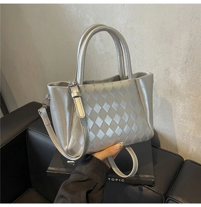 Detailed view of silver metallic tote bag featuring diamond quilted texture and silver hardware