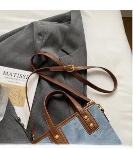 Detail of blue denim and brown leather bucket bag with adjustable gold buckle strap