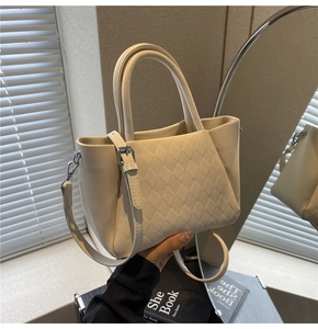 Close-up of diamond-quilted pattern on cream faux leather bucket bag with top handles