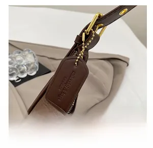 Detail view of dark brown leather strap and embossed brand tag with golden chain