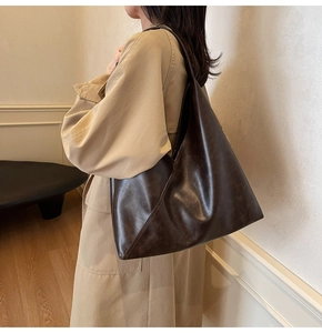 Detail view of the deep coffee minimalist hobo shoulder bag on model in a soft leather finish
