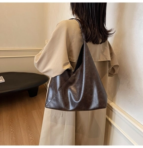 Detail of a large dark brown faux leather tote bag with unique diagonal stitching