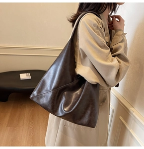 Deep brown oversized minimalist leather tote bag styled on model in beige trench coat