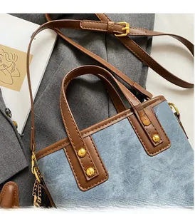 Close-up of vintage denim bucket bag with brown leather handles and gold rivet details