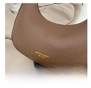 Close-up of brown lychee grain leather crescent bag with gold zipper and logo detail