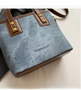 Detail of blue denim and brown leather tote with gold rivets and fashion embossing