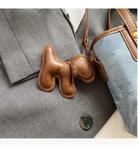Close-up of brown leather dog-shaped charm with fine stitching and golden metal clasp