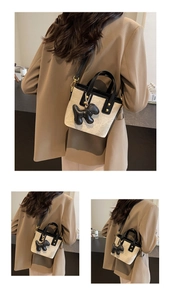 Detail of beige canvas mini bucket bag with black leather trim and poodle pendant