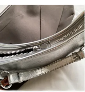 Close-up of silver metal zipper and crinkled texture on a metallic underarm bag