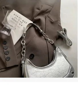 Close-up of silver crescent underarm bag with metallic texture and chunky chain detail
