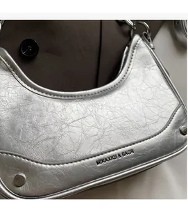 Detail of silver metallic wrinkled crescent bag with brand logo and metal rivets