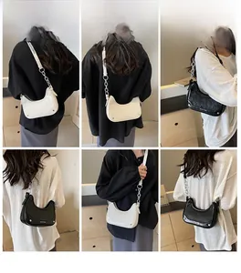 Model wearing vintage leather baguette bag in cream white and black with metal chain detail