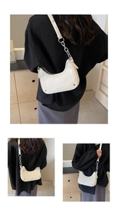 Detail view of cream leather crescent bag with silver rivets and metal chain strap