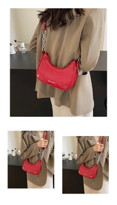 Detail of red hobo bag with silver chain strap and brand logo on leather finish