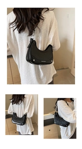 Detail of black crescent underarm bag with silver chain strap and matte finish leather