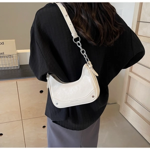 Detail of white half-moon underarm bag with glossy crinkled texture and silver chain strap
