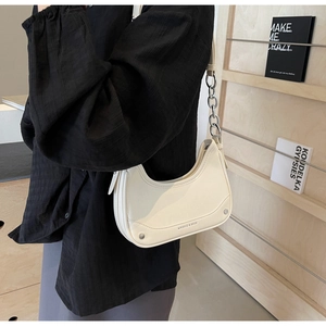 Close-up of cream hobo bag with silver chain detail on a model in black shirt