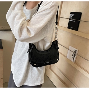 Detail showing black crinkle patent leather underarm bag with silver chain and rivet accents