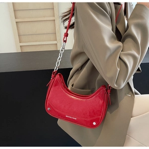 Detail of red patent leather underarm bag with silver chain strap and retro texture
