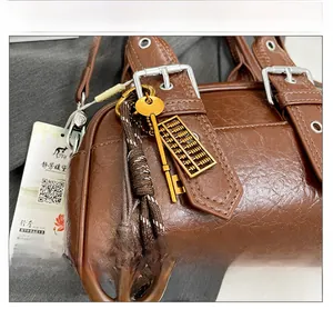 Détail du sac rétro en cuir marron avec breloques boulier doré et boucle en métal argenté