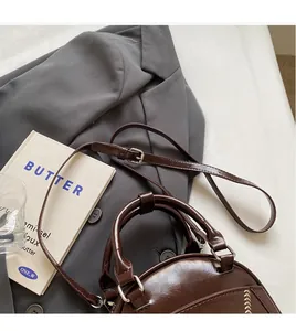 Close-up of brown vintage leather bag with adjustable strap and gold embroidery detail