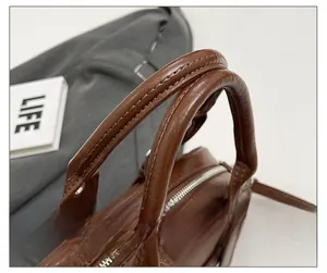 Détail des doubles poignées rondes sur sac à main en cuir marron à texture cirée