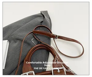 Détail de la bandoulière réglable en cuir marron avec une boucle en métal argenté