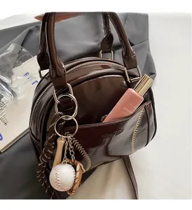 Detail of retro dark brown bowling bag with baseball stitching and mini glove charm