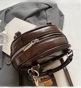 Detail view of smooth silver metal zipper and glossy dark brown PU leather on a retro bowling bag