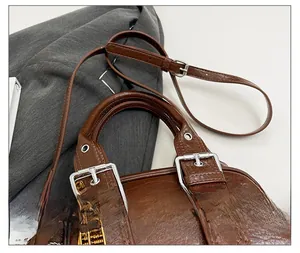 Détail du sac à main en cuir marron avec boucles argentées et breloques dorées