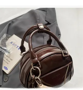 Detailed macro of dark brown shiny leather bowling bag with metallic charms and front pocket