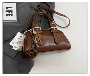 Détail d'un sac Boston vintage marron foncé avec boucles argentées et pendentifs dorés