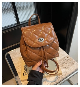 Détail d'un sac à dos en cuir verni marron matelassé avec fermoir tournant et cordon de serrage