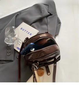 Detail of dark brown vintage bowling bag showing spacious interior for smartphone and lipstick