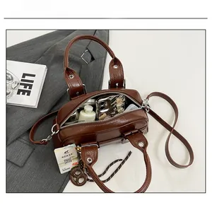 Détail du sac Boston marron foncé en cuir grainé montrant l'intérieur pour objets du quotidien