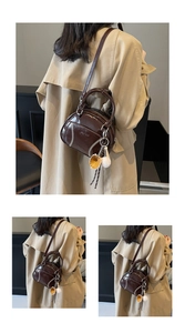Detailed macro view of vintage brown PU leather bag with contrast stitching and baseball charm