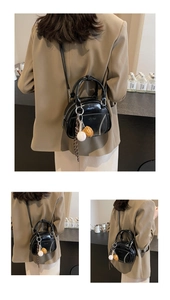 Detail of black mini boston bag with baseball stitching and themed charm on leather